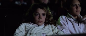 Movie still from “Anguish” (1987), directed by Bigas Luna – A young girl is sitting in a chair in front of a projector screen; Close Up shot, Low angle