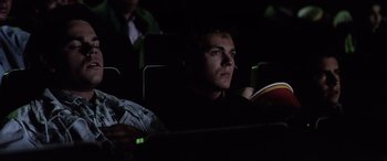 Movie still from “Anguish” (1987), directed by Bigas Luna – A man sitting in the dark in a movie theater; Close Up shot, Low angle