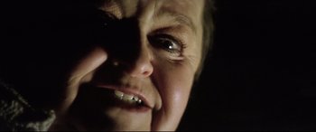 Movie still from “Anguish” (1987), directed by Bigas Luna – A person's face with a dark background; Extreme Close Up shot, Low angle
