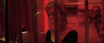 Movie still from “Anguish” (1987), directed by Bigas Luna – A woman smoking a cigarette in a room with red lighting; Close Up shot, Over the shoulder angle