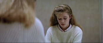 Movie still from “Anguish” (1987), directed by Bigas Luna – A young girl in a white sweater looks at her reflection in the mirror; Close Up shot, Over the shoulder angle