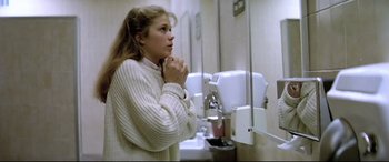 Movie still from “Anguish” (1987), directed by Bigas Luna – A woman standing in front of a bathroom sink; Medium shot, Low angle