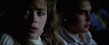 Movie still from “Anguish” (1987), directed by Bigas Luna – A young girl is looking into the camera; Close Up shot, Over the shoulder angle