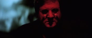 Movie still from “Anguish” (1987), directed by Bigas Luna – A man with glasses in a dark room; Close Up shot, Low angle