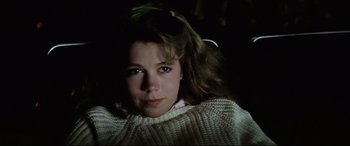 Movie still from “Anguish” (1987), directed by Bigas Luna – A young woman in a white sweater is looking at the camera; Close Up shot, High angle