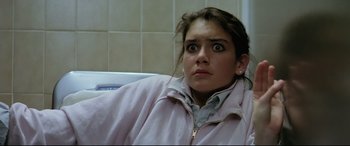 Movie still from “Anguish” (1987), directed by Bigas Luna – A woman sitting in front of a tiled wall looking surprised; Close Up shot, High angle