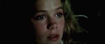 Movie still from “Anguish” (1987), directed by Bigas Luna – A young woman's face with a dark background; Close Up shot, High angle