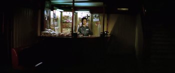 Movie still from “Anguish” (1987), directed by Bigas Luna – A woman standing in front of a counter in a store; Wide shot, Low angle