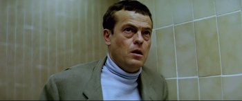 Movie still from “Anguish” (1987), directed by Bigas Luna – A person wearing a suit and tie; Close Up shot, Low angle