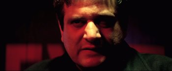 Movie still from “Anguish” (1987), directed by Bigas Luna – A person's face in a dark room; Close Up shot, Low angle