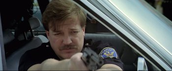Movie still from “Anguish” (1987), directed by Bigas Luna – A police officer holding a gun in a car; Close Up shot, Low angle