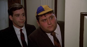 Movie still from “National Lampoon's Animal House” (1978), directed by John Landis – Two men in suits and a yellow and blue hat; Close Up shot, Over the shoulder angle