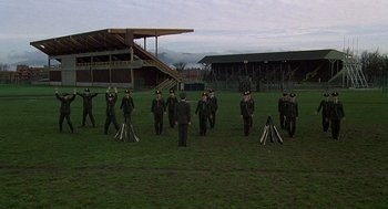 Movie still from “National Lampoon's Animal House” (1978), directed by John Landis – A group of men standing on top of a grass covered field; Extreme Wide shot, Low angle