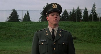 Movie still from “National Lampoon's Animal House” (1978), directed by John Landis – A man in a military uniform standing in front of a fence; Close Up shot, Low angle