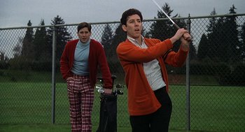 Movie still from “National Lampoon's Animal House” (1978), directed by John Landis – A man holding a golf club while standing next to a woman; Medium shot, Low angle