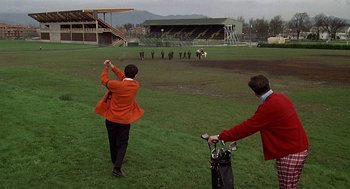 Movie still from “National Lampoon's Animal House” (1978), directed by John Landis – Two men are playing golf on a field; Extreme Wide shot, Low angle