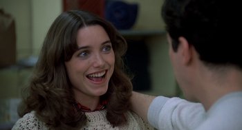 A young woman smiling while a man is touching her shoulder