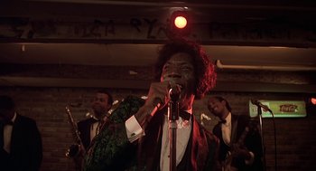 A man in a suit and bow tie singing into a microphone