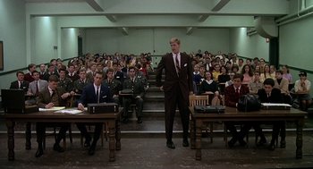 Movie still from “National Lampoon's Animal House” (1978), directed by John Landis – A man in a suit stands in front of an audience; Wide shot, High angle