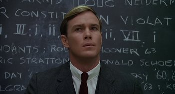 Movie still from “National Lampoon's Animal House” (1978), directed by John Landis – A man wearing a suit and tie standing in front of a chalkboard; Close Up shot, Over the shoulder angle