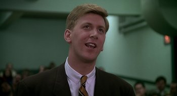 Movie still from “National Lampoon's Animal House” (1978), directed by John Landis – A man in a suit and tie smiling for the camera; Close Up shot, Low angle