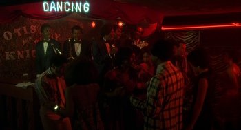 Movie still from “National Lampoon's Animal House” (1978), directed by John Landis – A group of people standing in a room with lights on; Extreme Wide shot, High angle