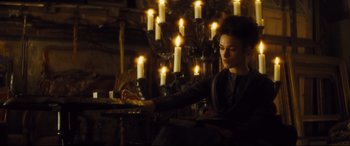 Movie still from “Anna Karenina” (2012), directed by Joe Wright – A woman sitting in front of a bunch of lit candles; Medium shot, High angle