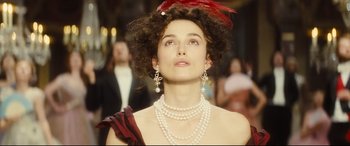 Movie still from “Anna Karenina” (2012), directed by Joe Wright – A woman wearing pearls and a red feather hat; Close Up shot, Low angle