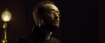 Movie still from “Anna Karenina” (2012), directed by Joe Wright – A person wearing glasses and a beard; Close Up shot, Low angle