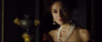 Movie still from “Anna Karenina” (2012), directed by Joe Wright – A woman wearing pearls in a dark room; Close Up shot, Over the shoulder angle