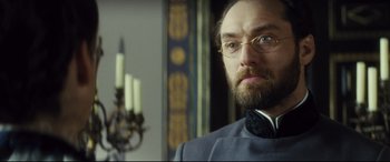 Movie still from “Anna Karenina” (2012), directed by Joe Wright – A man with a goatee wearing glasses and a suit; Close Up shot, Low angle