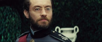 Movie still from “Anna Karenina” (2012), directed by Joe Wright – A person wearing glasses and a uniform; Close Up shot, Over the shoulder angle