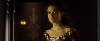 Movie still from “Anna Karenina” (2012), directed by Joe Wright – A woman in a red and white dress looking at the camera; Close Up shot, Over the shoulder angle