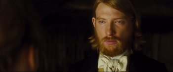 Movie still from “Anna Karenina” (2012), directed by Joe Wright – A person wearing a suit and bow tie; Close Up shot, Over the shoulder angle