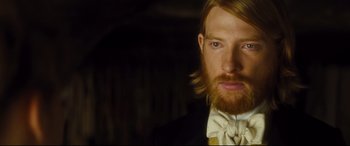 Movie still from “Anna Karenina” (2012), directed by Joe Wright – A person wearing a suit and bow tie; Close Up shot, Over the shoulder angle