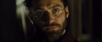 Movie still from “Anna Karenina” (2012), directed by Joe Wright – A person wearing glasses and a beard; Close Up shot, Low angle