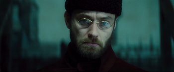 Movie still from “Anna Karenina” (2012), directed by Joe Wright – A person wearing glasses and a hat; Close Up shot, Low angle