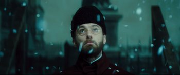 Movie still from “Anna Karenina” (2012), directed by Joe Wright – A man wearing glasses and a hat looking up; Close Up shot, Low angle