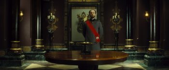 Movie still from “Anna Karenina” (2012), directed by Joe Wright – A man standing in front of a mirror in a room; Wide shot, Low angle