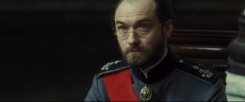 Movie still from “Anna Karenina” (2012), directed by Joe Wright – A person wearing glasses and a uniform; Close Up shot, Low angle