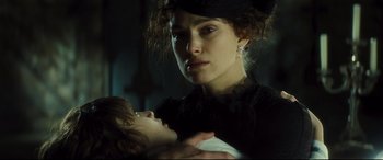 Movie still from “Anna Karenina” (2012), directed by Joe Wright – A woman holding a baby in a dark room; Close Up shot, Low angle