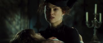 Movie still from “Anna Karenina” (2012), directed by Joe Wright – A woman holding a baby in her arms in a dark room; Close Up shot, Over the shoulder angle
