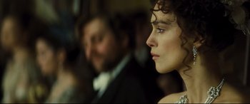 Movie still from “Anna Karenina” (2012), directed by Joe Wright – A woman's face with a man in the background; Close Up shot, Over the shoulder angle