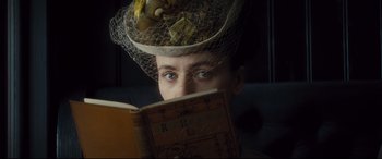 Movie still from “Anna Karenina” (2012), directed by Joe Wright – A person wearing a hat and reading a book; Close Up shot, High angle