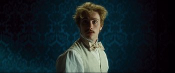 Movie still from “Anna Karenina” (2012), directed by Joe Wright – A man with a bow tie standing in front of a blue wall; Close Up shot, Low angle