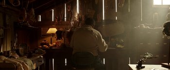 Movie still from “Annabelle: Creation” (2017), directed by David F. Sandberg – A man sitting at a table in front of a lamp; Wide shot, Low angle