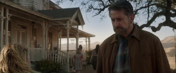 Movie still from “Annabelle: Creation” (2017), directed by David F. Sandberg – A man standing in front of a house with people in the background; Medium shot, Over the shoulder angle