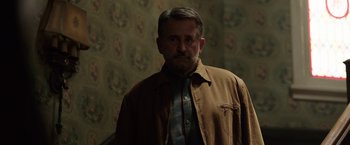Movie still from “Annabelle: Creation” (2017), directed by David F. Sandberg – An older man wearing a brown jacket standing in front of a wall; Medium shot, Over the shoulder angle