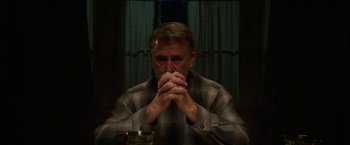 Movie still from “Annabelle: Creation” (2017), directed by David F. Sandberg – A man sitting at a table with his hands clasped together; Medium shot, Low angle