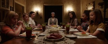 Movie still from “Annabelle: Creation” (2017), directed by David F. Sandberg – A group of people sitting at a table with plates of food on it; Medium shot, High angle
